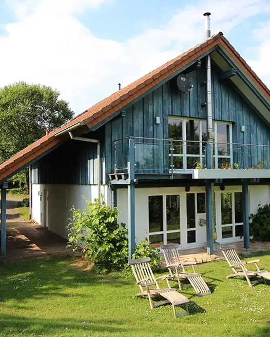 Ein zweistöckiges Ferienhaus mit Balkon und Terrasse im Grünen