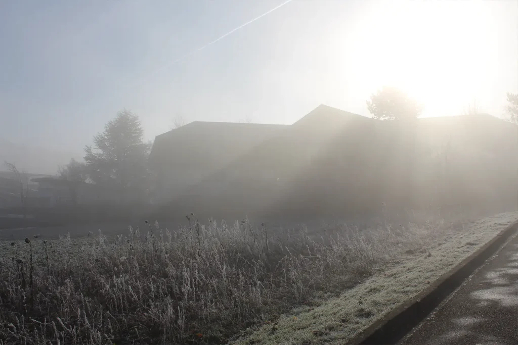 Gebäude im Nebel, durch den ein Sonnenstrahl scheint