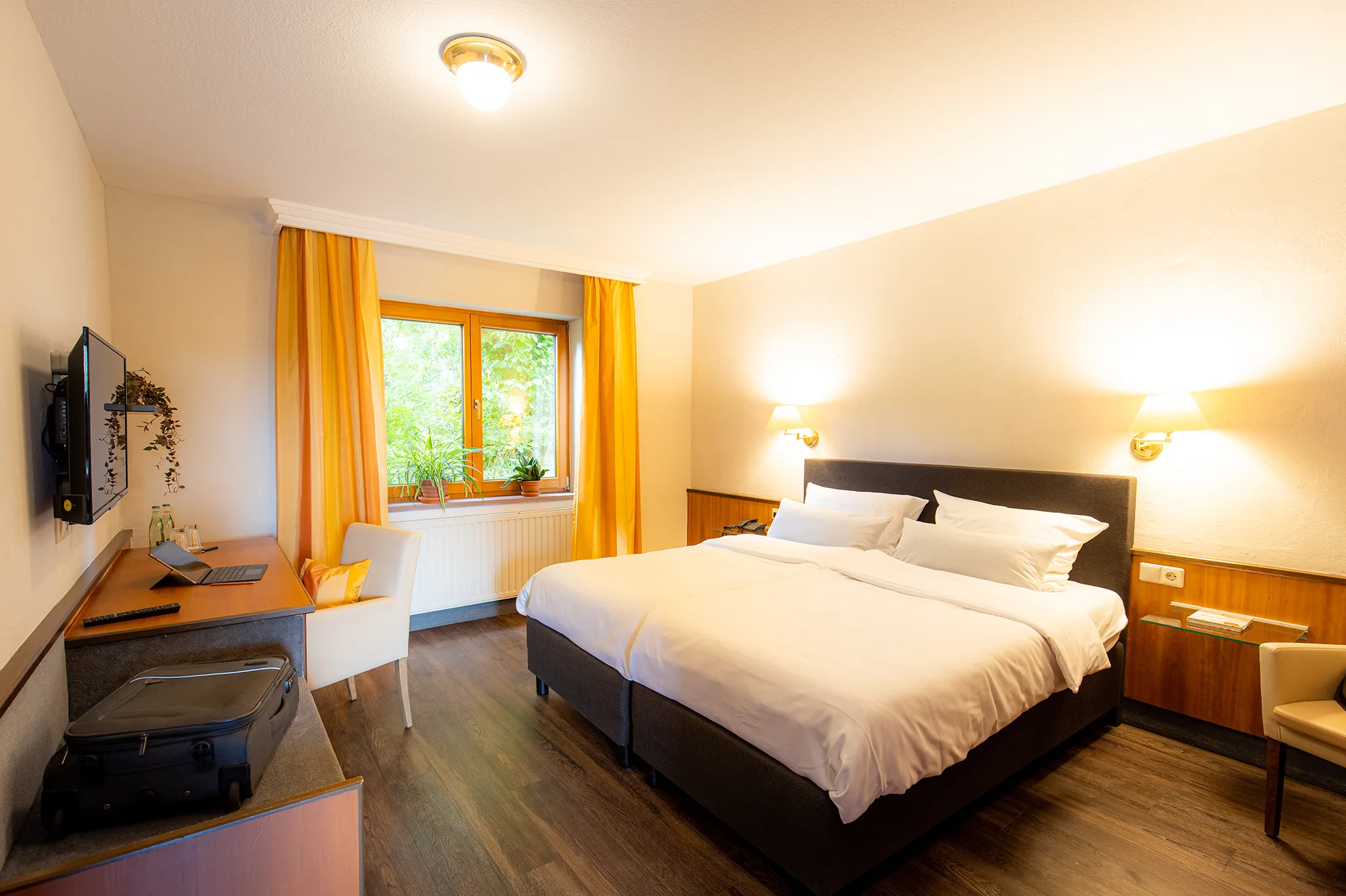 Hotelzimmer mit Doppelbett, Fernseher und Schreibtisch