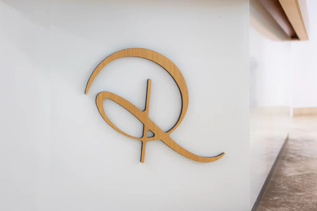 Ein aus Holz geschnitztes R auf einer weißen Wand