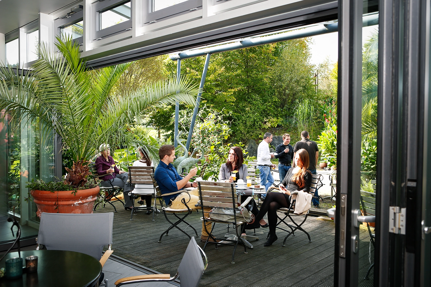 Eine Gruppe Menschen auf einer Terrasse im Grünen bei einer Kaffeepause