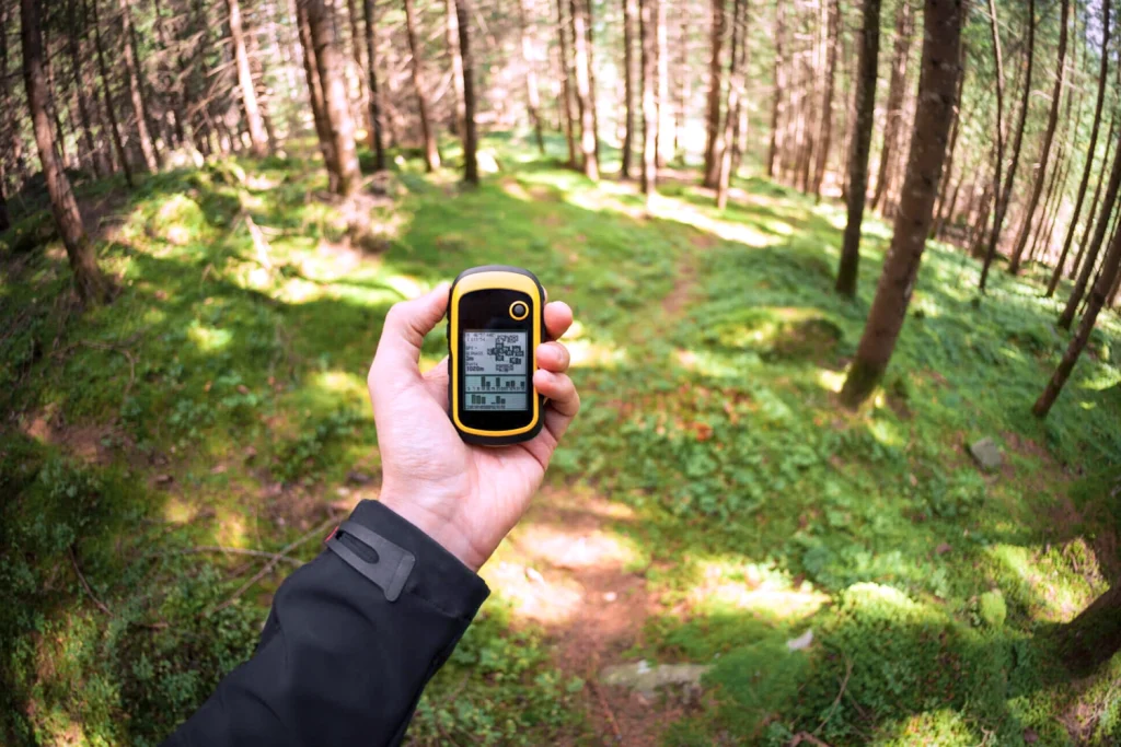 Eine Hand hält ein GPS Gerät in einem Wald