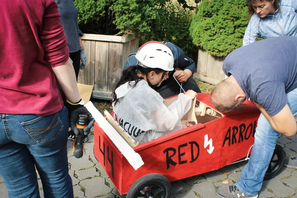Eine Frau in einem roten, selbst gebauten Gefährt aus Holz