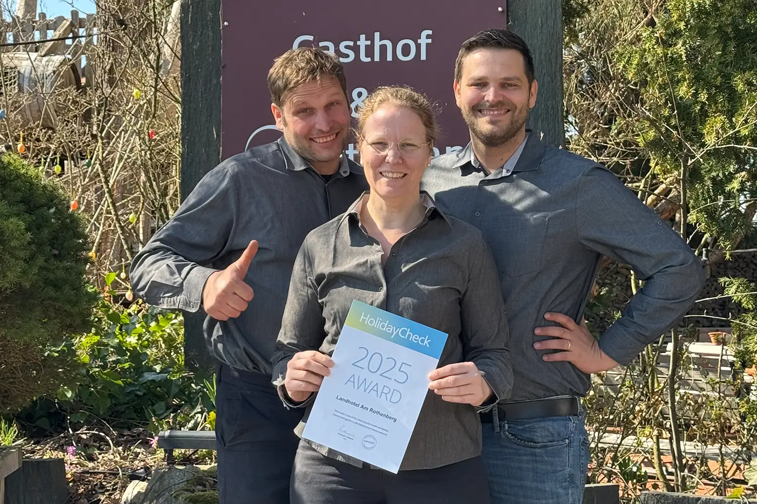 zwei Männer und eine Frau, die gemeinsam eine Urkunde präsentieren