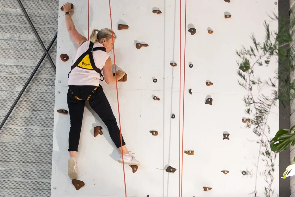 Eine Frau, die indoor an einer Kletterwand klettert