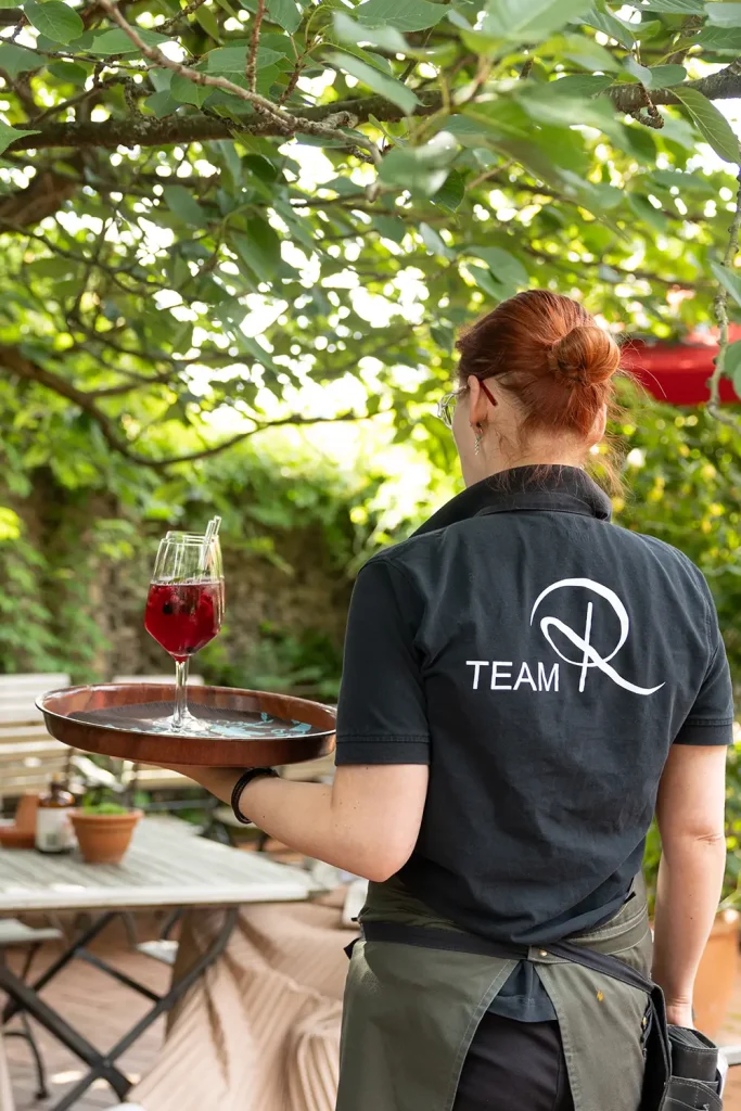 Kellnerin trägt ein Weinglas gefüllt mit einem Cocktail auf einem Tablet