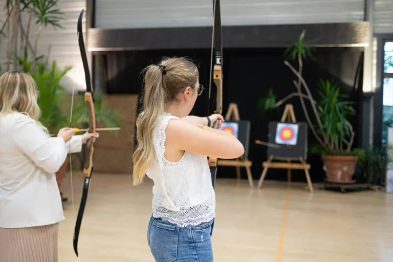 Zwei Frauen zielen mit Pfeil und Bogen auf eine Zielscheibe