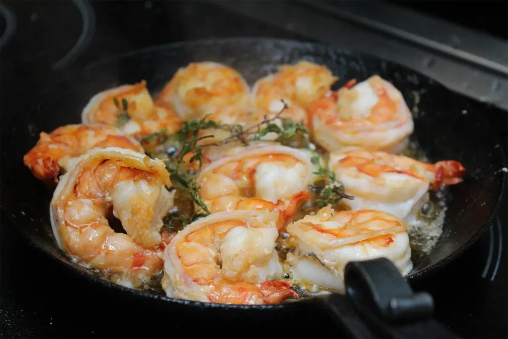 Garnelen werden in einer Pfanne geschmort mit frischen Kräutern