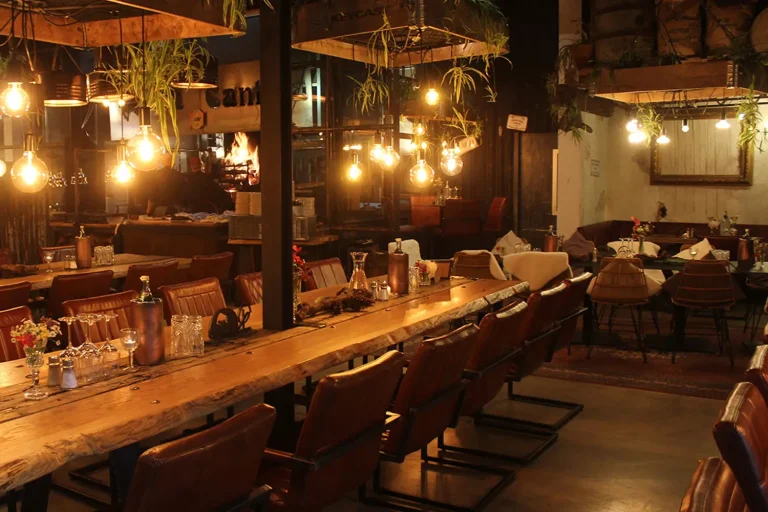 langer Holztisch mit gemütlichen Lounge-Stühlen in einem Restaurant, gemütliche Stimmung durch gedämpftes Licht