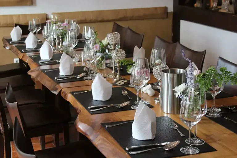 ein rustikaler Holztisch, der feierlich mit Servietten und Weingläsern und Blumendekoration eingedeckt ist