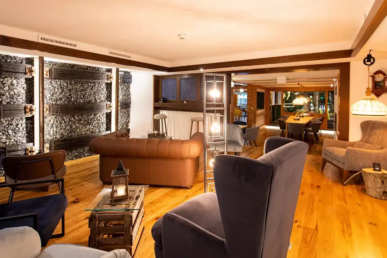 Eine gemütliche Lounge mit bequemen Sesseln und Sofas, im Hintergrund ist der Zugang zu einer Kegelbahn