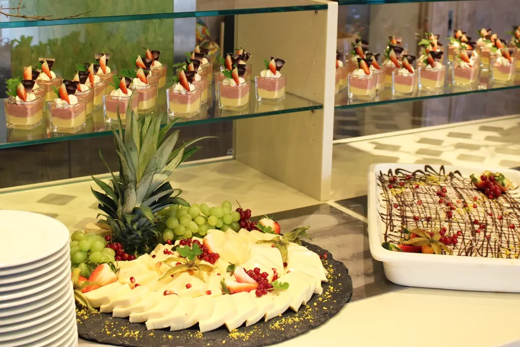 Blick auf ein Dessertbuffet mit Cremespeisen portioniert in Gläsern, Käse, Tellern