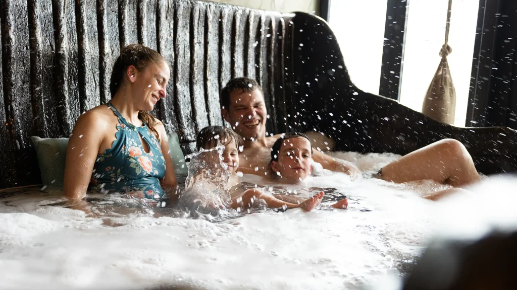 Ein Paar mit zwei Kindern badet gemeinsam in einer großen schwarzen Wanne