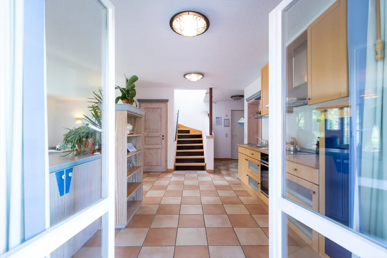 Blick von außen in die Küche eines Hauses, im Hintergrund sieht man einen Treppenaufgang