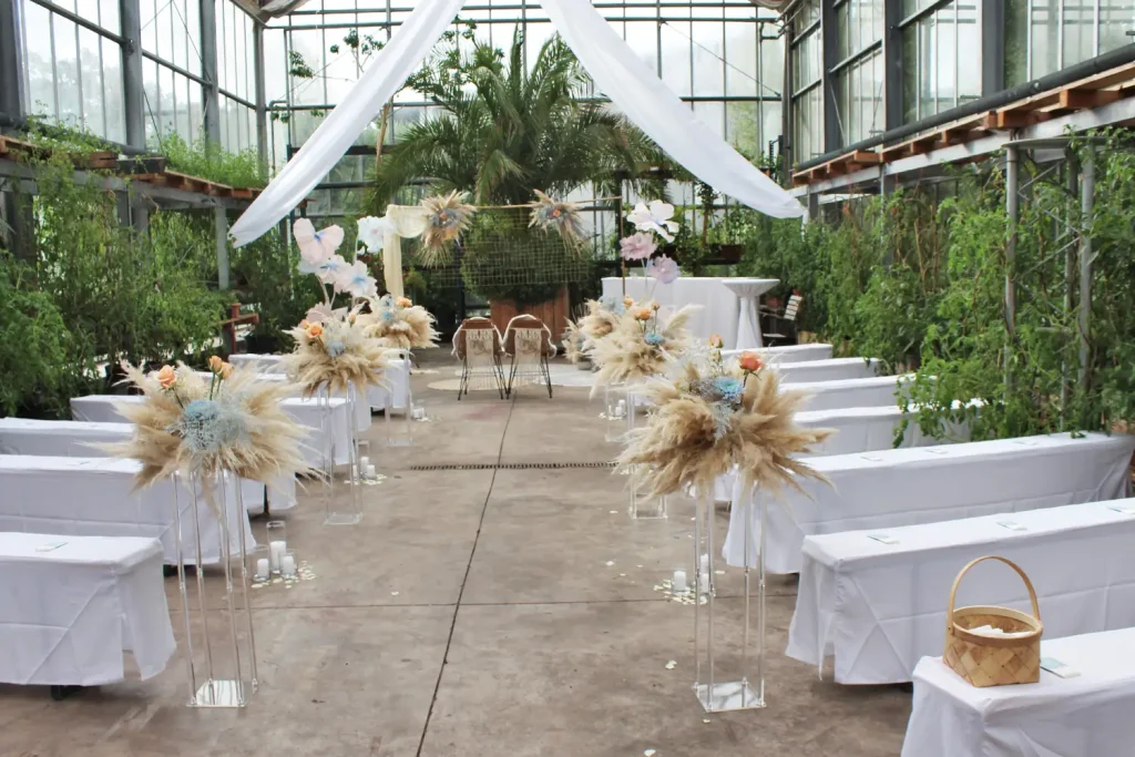Ein großes Gewächshaus, in dem Stühle und Dekoration für eine Trauungszeremonie bereitstehen