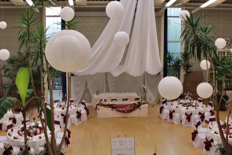 Festlich weiß geschmückte Tische, stimmungsvolles Licht und Stoffbahnen und weiße Lampions, die von der Decke hängen