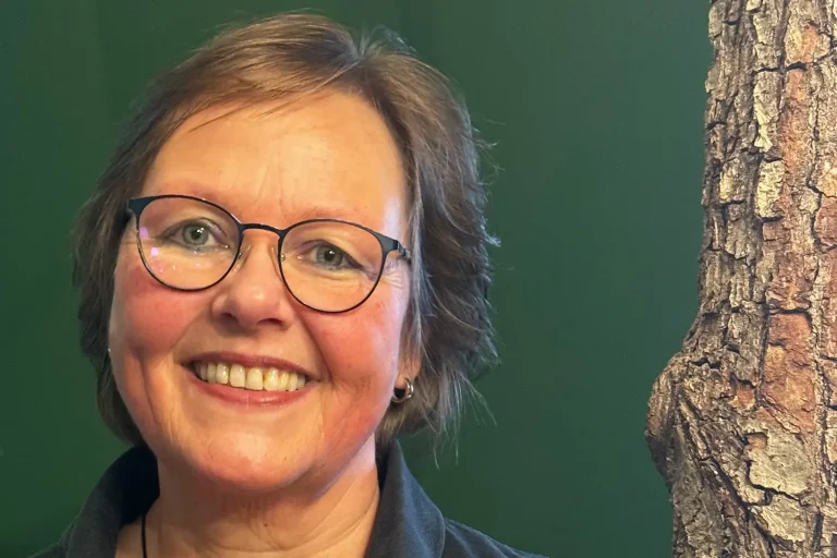 Eine dunkelhaarige Frau mit Brille vor einer grünen Wand