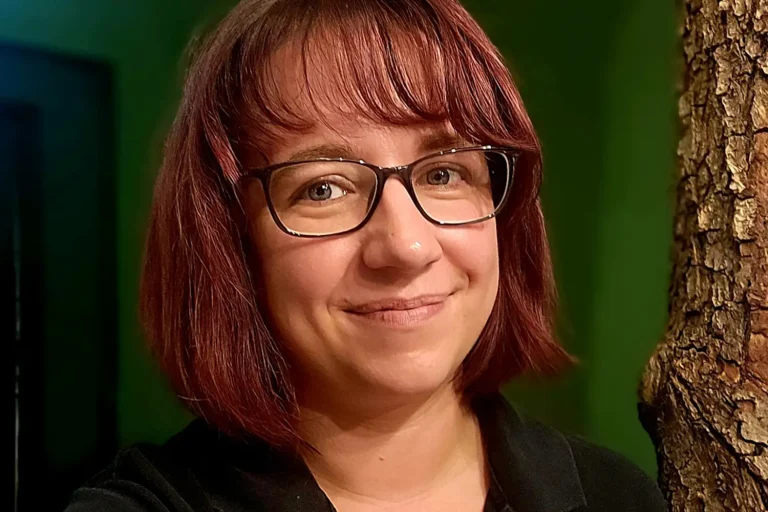 Eine dunkelhaarige Frau mit Brille vor einer grünen Wand