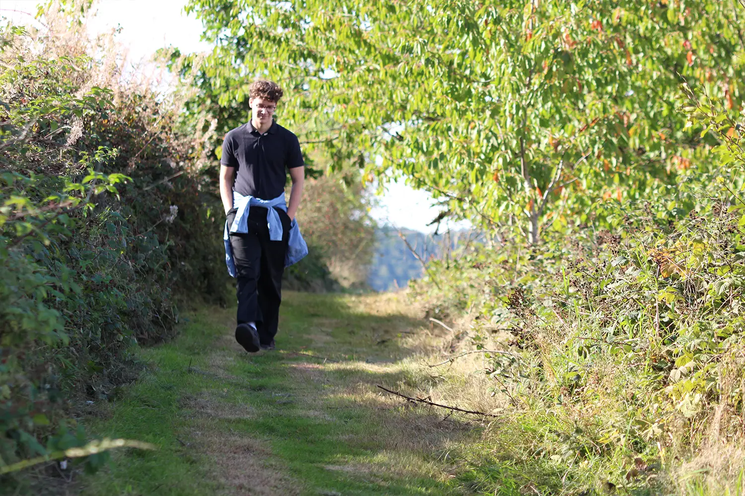 Ein junger Mann, der einen Feldweg entlangspaziert
