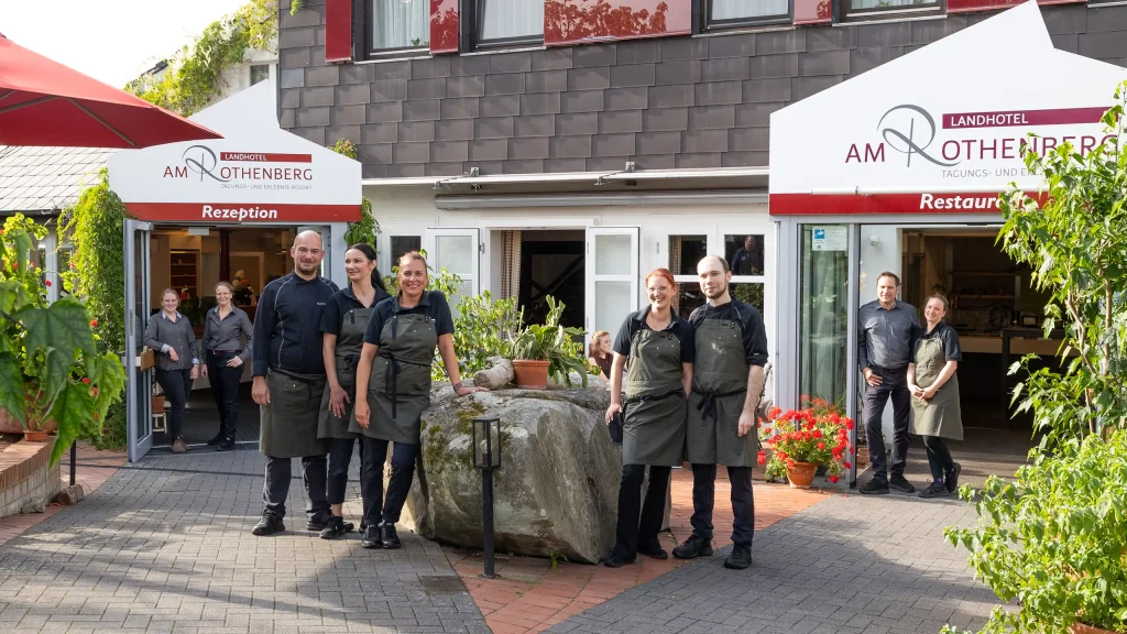 Mitarbeitende in Arbeitskleidung, die sich vor dem Hoteleingang zu einem Gruppenbild aufgestellt haben