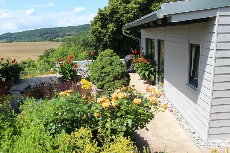 Terrasse mit vielen Kübelpflanzen und Blick auf Wald und Felder