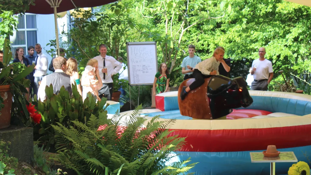 Großfamilie bei einem Treffen, ein Junge reitet auf einem mechanischen Bullen