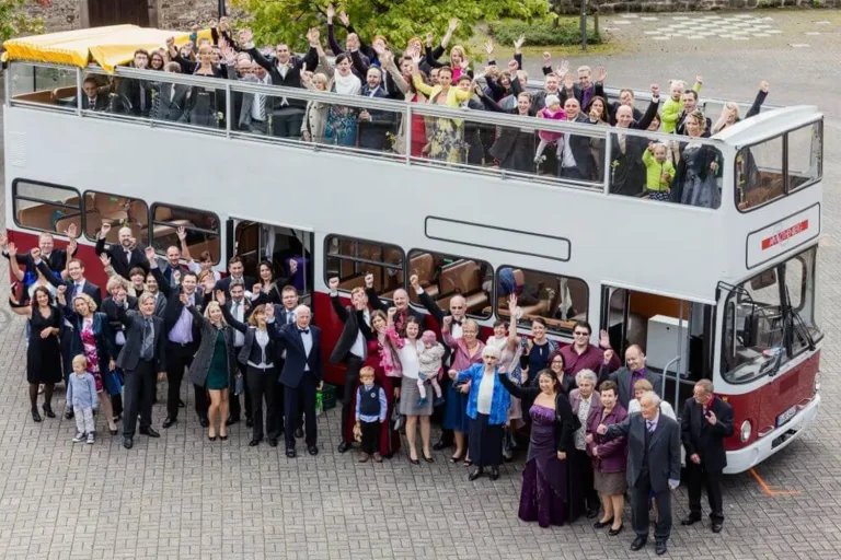 Eine Party-Gesellschaft, die sich in und vor einem großen Bus für ein Foto aufgestellt haben