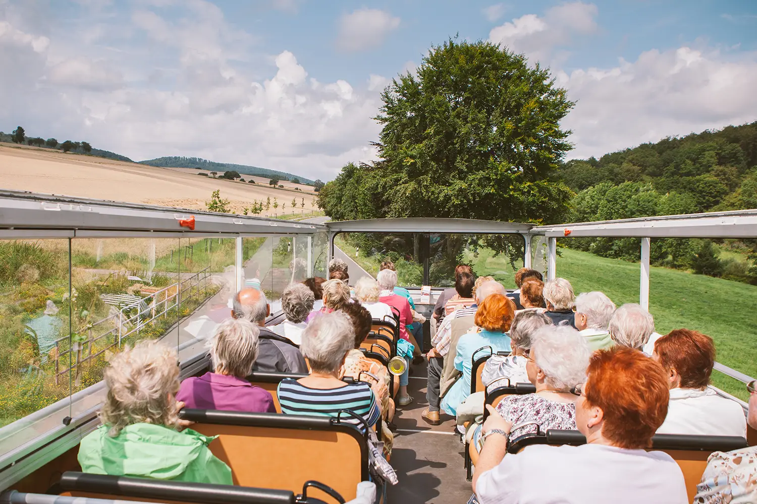 Eine Gruppe Menschen, die eine Ausflugsfahrt mit einem Cabrio-Bus mit offenem Verdeck unternimmt