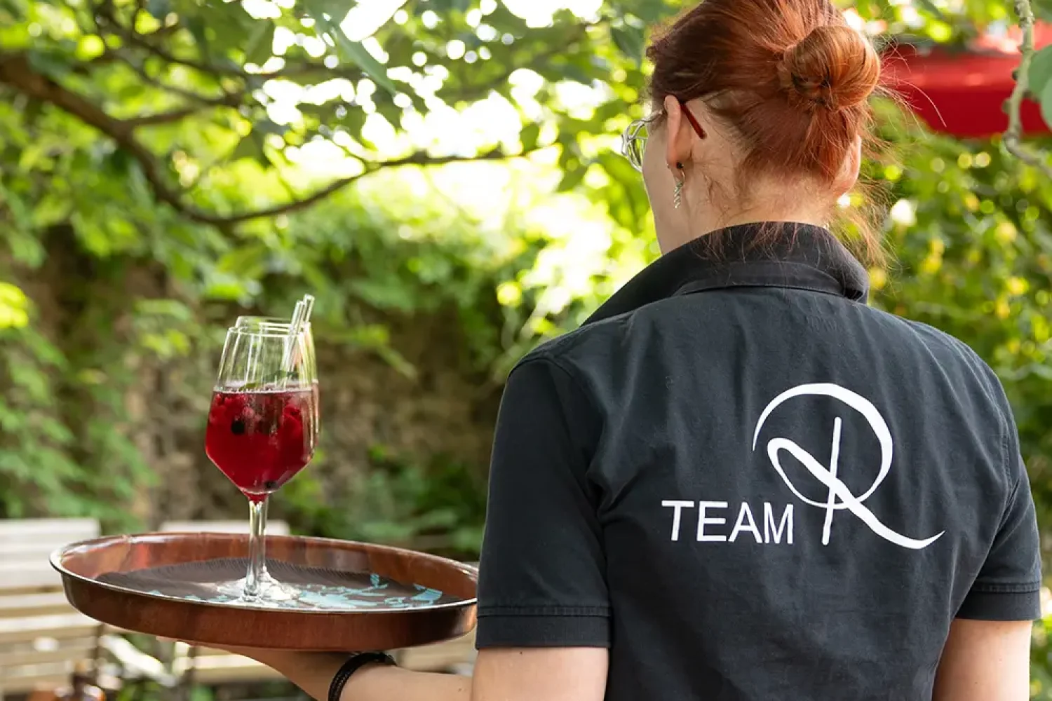 Kellnerin trägt ein Weinglas gefüllt mit einem Cocktail auf einem Tablet